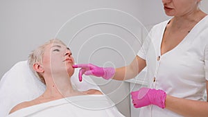 Adult woman at a cosmetologist's appointment in a beauty salon. The beautycian examines the client's face. Slow