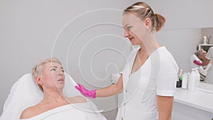 An adult woman at a cosmetologist's appointment in a beauty salon. Two women communicate with each other. Slow