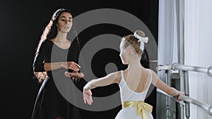 Adult woman dancer dance teacher coach tells teenage girl ballerina advice helps move gracefully with hands near ballet