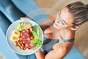 Adult woman eating healthy lunch and sitting on yoga mat