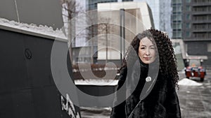 adult woman with extravagant hairstyle is walking in city at winter, portrait of townswoman dressed fur coat photo