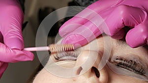 Adult woman face on modern eyelash lamination procedure in a professional beauty salon. master washes off the black