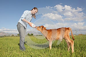 Woman feeding baby calf a bottle