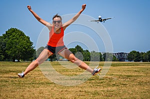 Adult woman at Gravelly Point Park in Washington DC jumps as an airplane flies in for a landing at the DCA Reagan International