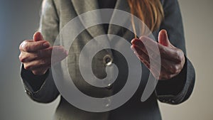 An adult woman in a gray business suit stands and holds her hands as if she were holding a tablet. No face. Close-up of