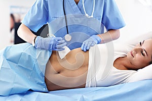 Adult woman having abdomen ultrasound tests at female doctor`s office