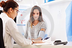 Adult woman having blood pressure test during visit at female doctor`s office