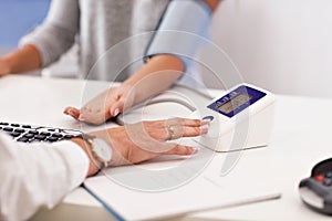 Adult woman having blood pressure test during visit at female doctor`s office