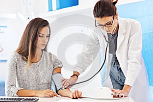 Adult woman having blood pressure test during visit at female doctor`s office