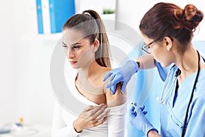 Adult woman having injection during visit at female doctor`s office