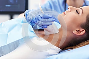 Adult woman having thyroind ultrasound test at female doctor`s office