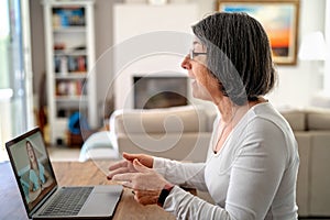 Adult  woman having video chat online on laptop with her granddaughter at home