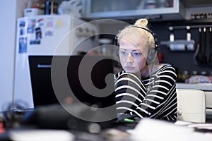 Adult woman in her casual home clothing working and studying remotely from her small flat late at night.