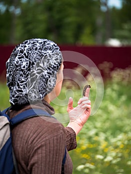 Adult woman holding at arm's length a large hairy caterpillar