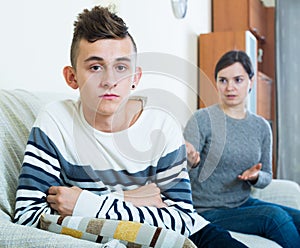 Adult woman lecturing unpleased teenager in home interior