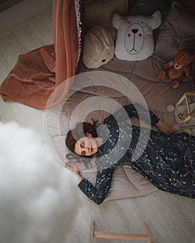 An adult woman lies near a children`s tent, smiling, remembering her childhood.