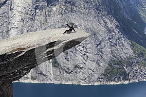 Adult woman lying on Trolltunga cliff on his back. Taking selfie picture with smartphone. Norway