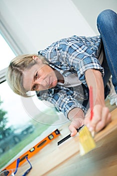 Adult woman measuring wooden board with tape measure