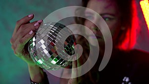 Adult woman in nightclub, portrait with disco ball in hands, new year party