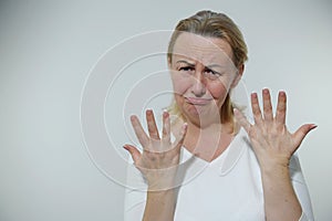 adult woman is offended upset like child she put out fingers with fan of both hands looks into frame completely frowning photo