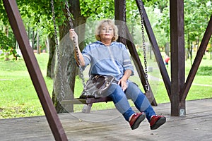 An adult woman in a park is swinging on a swing alone,