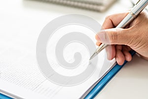 adult woman person hand holding pen writing or signing document on clipboard indoor at company, closeup finger professional