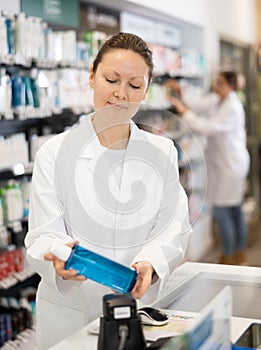 Adult woman pharmacist scanning cosmetics at checkout