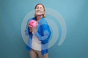 adult woman with a piggy bank of money on a blue background with copy space