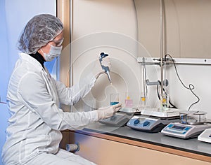 Adult woman protective glasses and medical mask holding in his hand glass flask with blue liquid and in the other hand she is hold