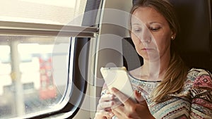 Adult woman reading a book on a mobile phone in the train.