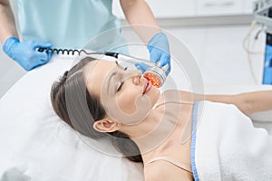 Adult woman receiving facial treatment in cosmetology clinic