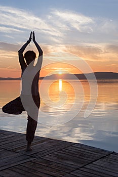 Adult woman relax while doing yoga exercises on Lake Balaton