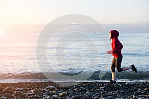 Adult woman runner running on sunrise seaside. Healthy lifestyle