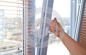 Adult woman`s hand opening a window for ventilation.