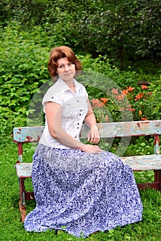 Adult woman sitting on a bench in the garden