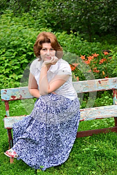 Adult woman sitting on a bench in the garden