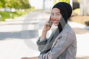 Adult woman smiling talking with her phone in the park looking at camera