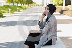 Adult woman smiling talking with her phone in the park looking at camera