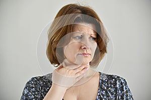 Adult woman with a sore throat on light background