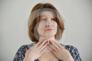 Adult woman with a sore throat on light background