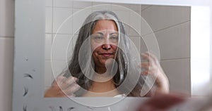 Adult woman standing in front of mirror after straightening and styling her long hair