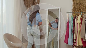 Adult woman succeeds putting on tight jeans, dancing happily indoors