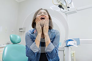 Adult woman suffering from toothache and complaining during visit to professional dentist.