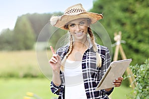 Adult woman with tablet examining plants