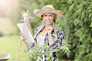 Adult woman with tablet examining plants