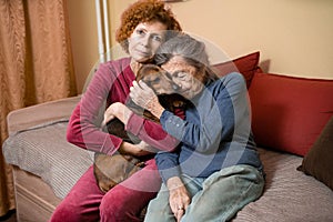 Adult woman takes care of her older mother with dementia, spending time at home with parent and dogs, smiling and