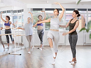 Adult woman teacher correcting beginning dancers