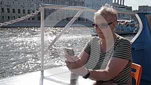 Adult woman on tourist ship holding smartphone