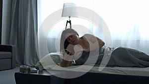 Adult woman waking up with mobile alarm clock