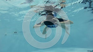 An adult woman wearing virtual reality glasses swims, poses and plays underwater in the pool. The concept of immersion